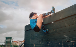 woman climbing wall showing how to overcome obstacles