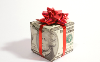 A box wrapped in money with a red bow symbolizing creative ways to save money at Christmas